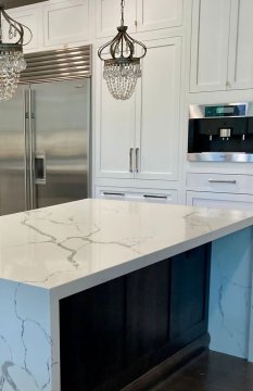 The sleek, white countertop, adorned with delicate gray vein...